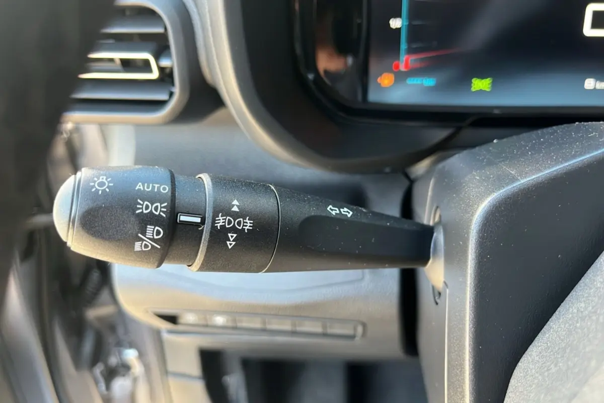 Gros plan sur la commande des feux et clignotants à gauche du volant dans l’habitacle du Citroën Berlingo gris 2025.