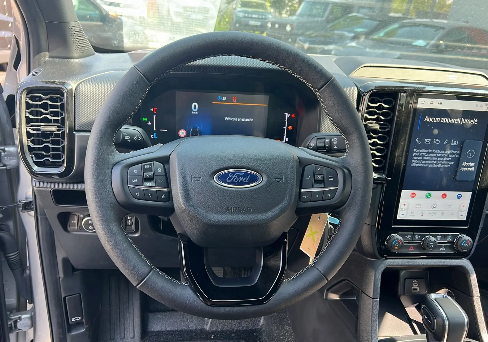 Vue intérieure centrée sur le volant cuir multifonctions et l'écran tactile du Ford Ranger gris iconic 2025.