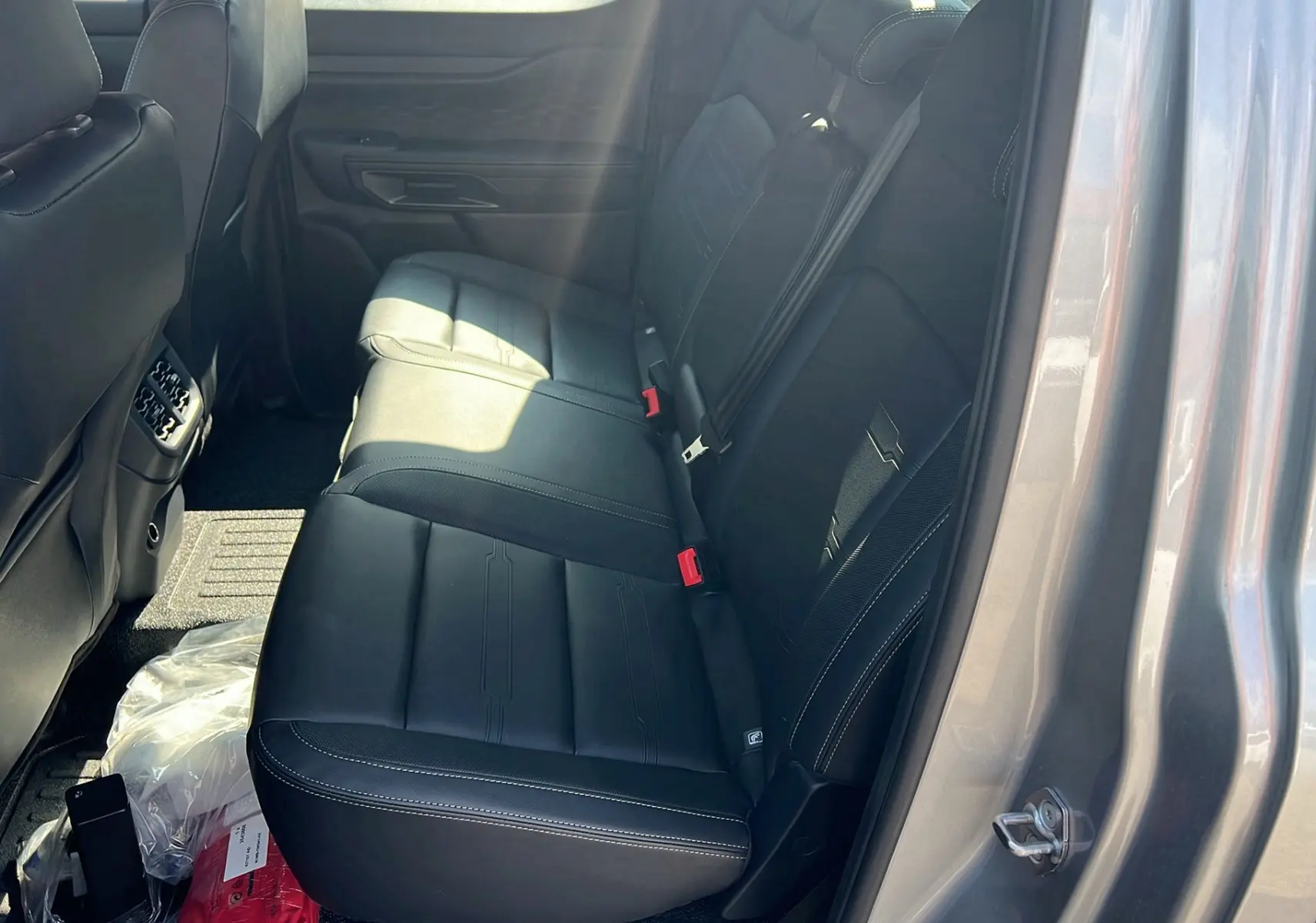 Vue côté droit de la banquette arrière en cuir noir du Ford Ranger 2025 gris iconic avec ceinture rouge visible.