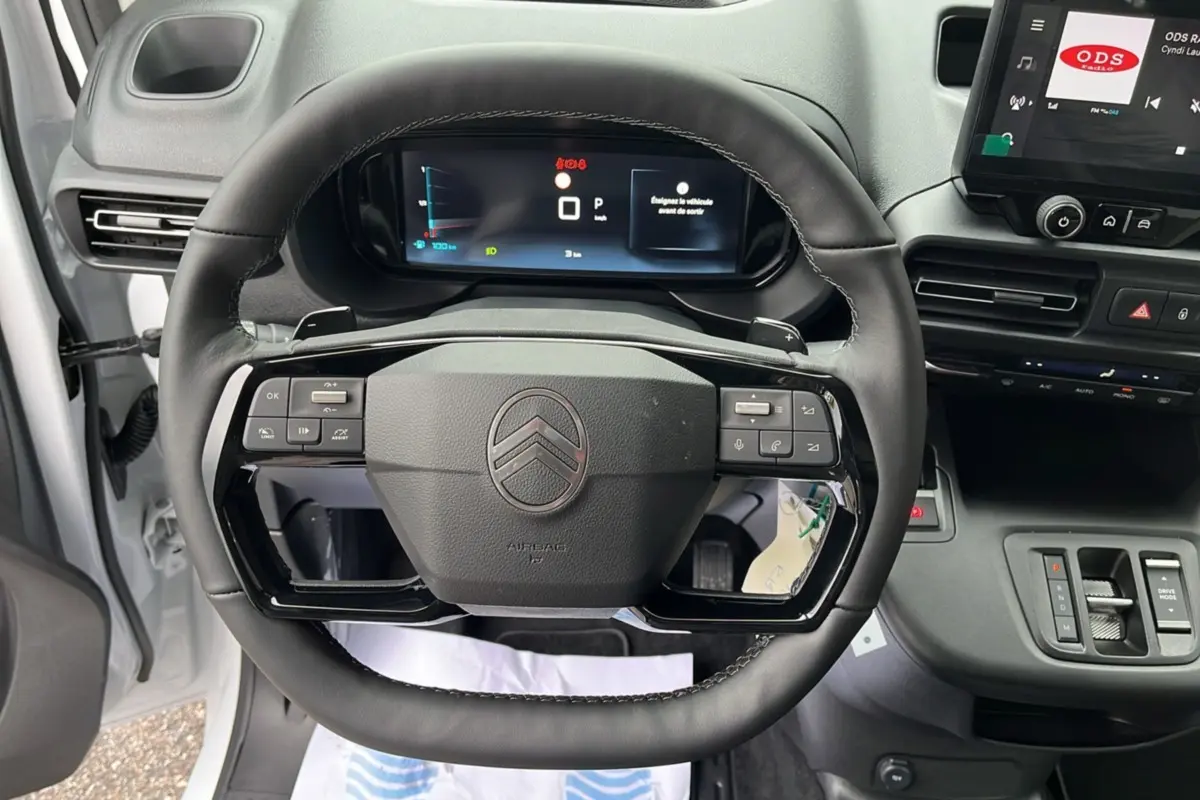 Vue intérieure centrée sur le volant cuir multifonctions du Citroën Berlingo Kaolin white avec tableau de bord numérique.