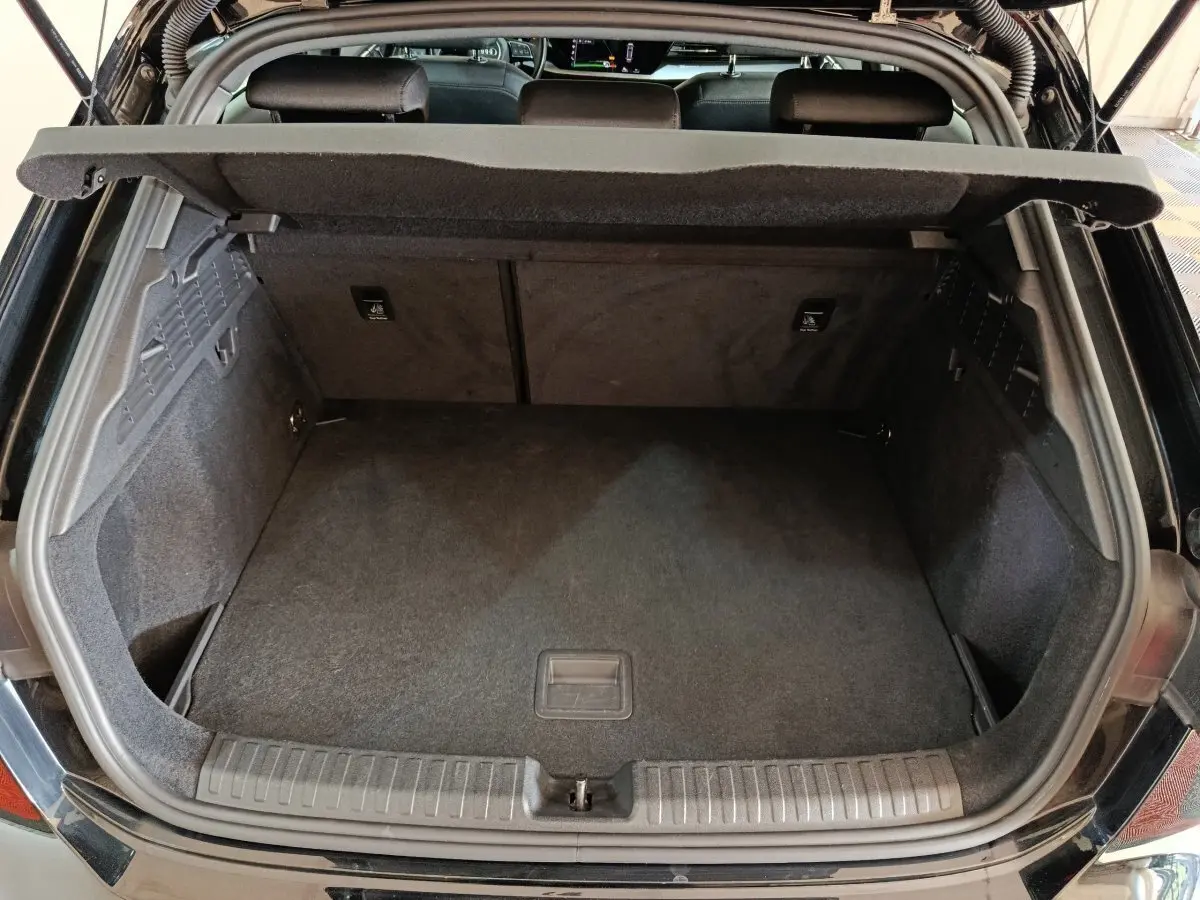 Coffre ouvert vu de l'arrière d'une Audi A3 noire 2023, espace de rangement propre et bien fini.