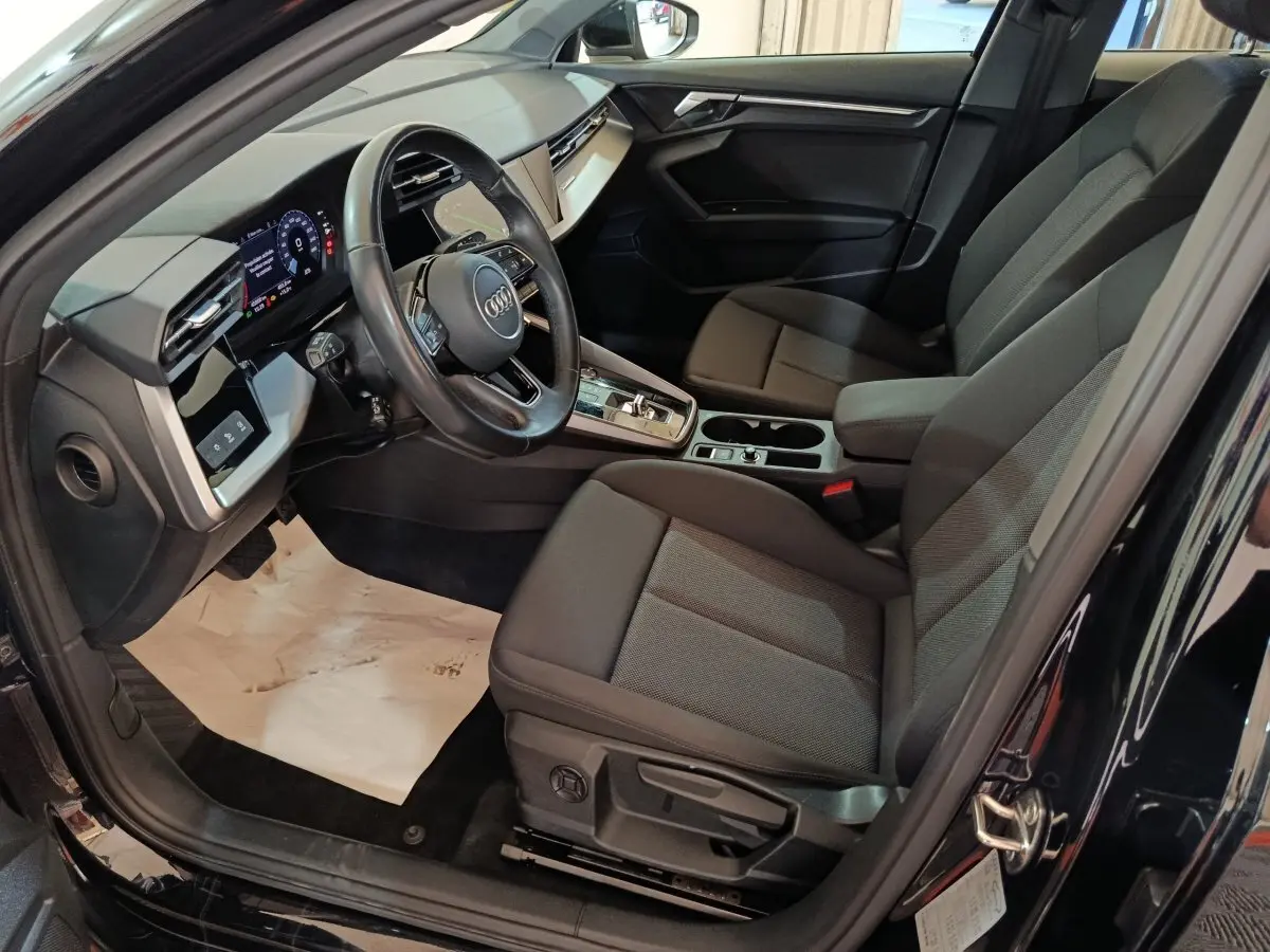 Vue intérieure côté conducteur de l'Audi A3 35 TDI noire, avec tableau de bord digital et sièges tissu gris.