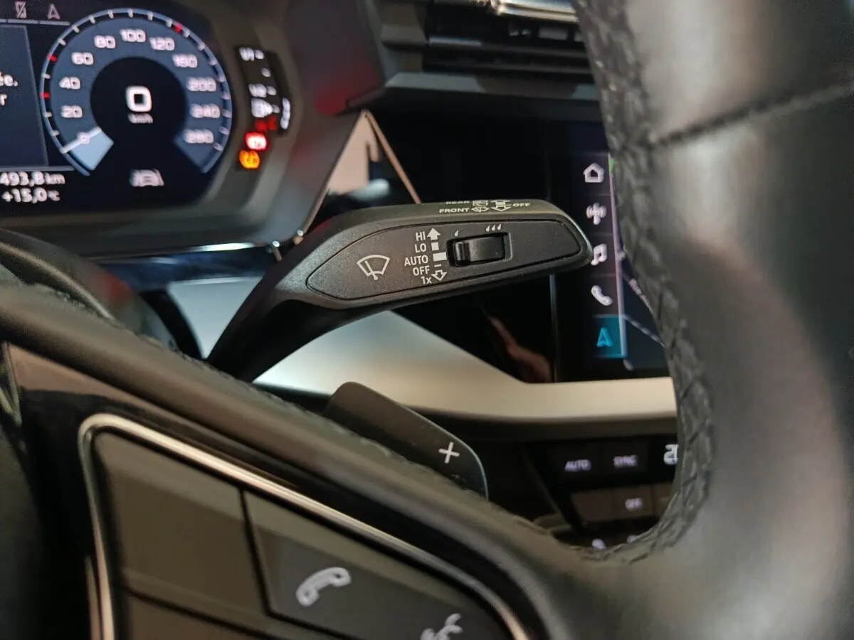 Gros plan sur la manette d’essuie-glace à gauche du volant cuir noir de l’Audi A3 35 TDI 2023 avec tableau de bord digital.