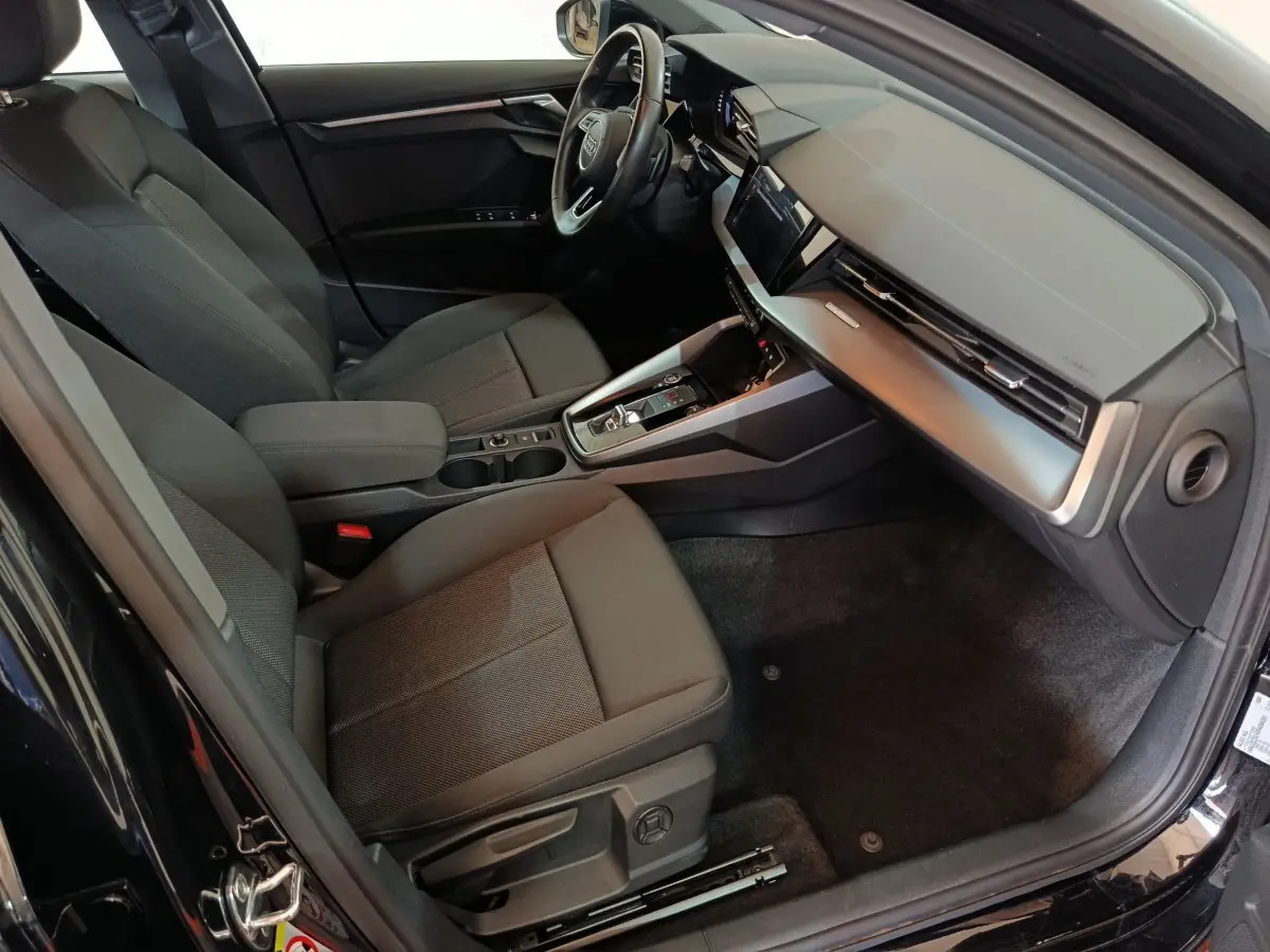 Vue intérieure côté conducteur de l'Audi A3 35 TDI 2023 noire, avec tableau de bord moderne et sièges tissu gris.