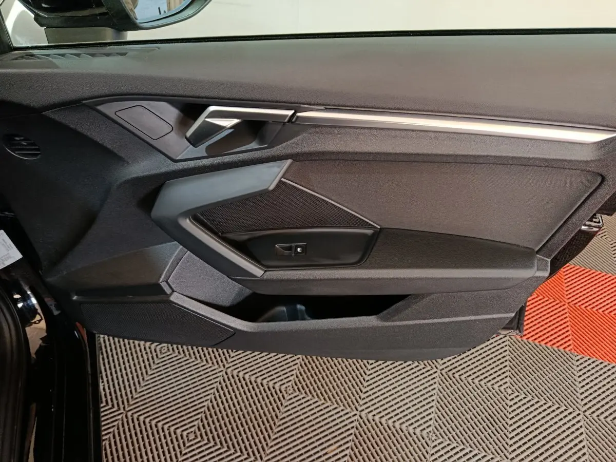 Vue intérieure côté gauche de la porte noire d’une Audi A3 35 TDI 150 S tronic Business Line avec poignée argentée.