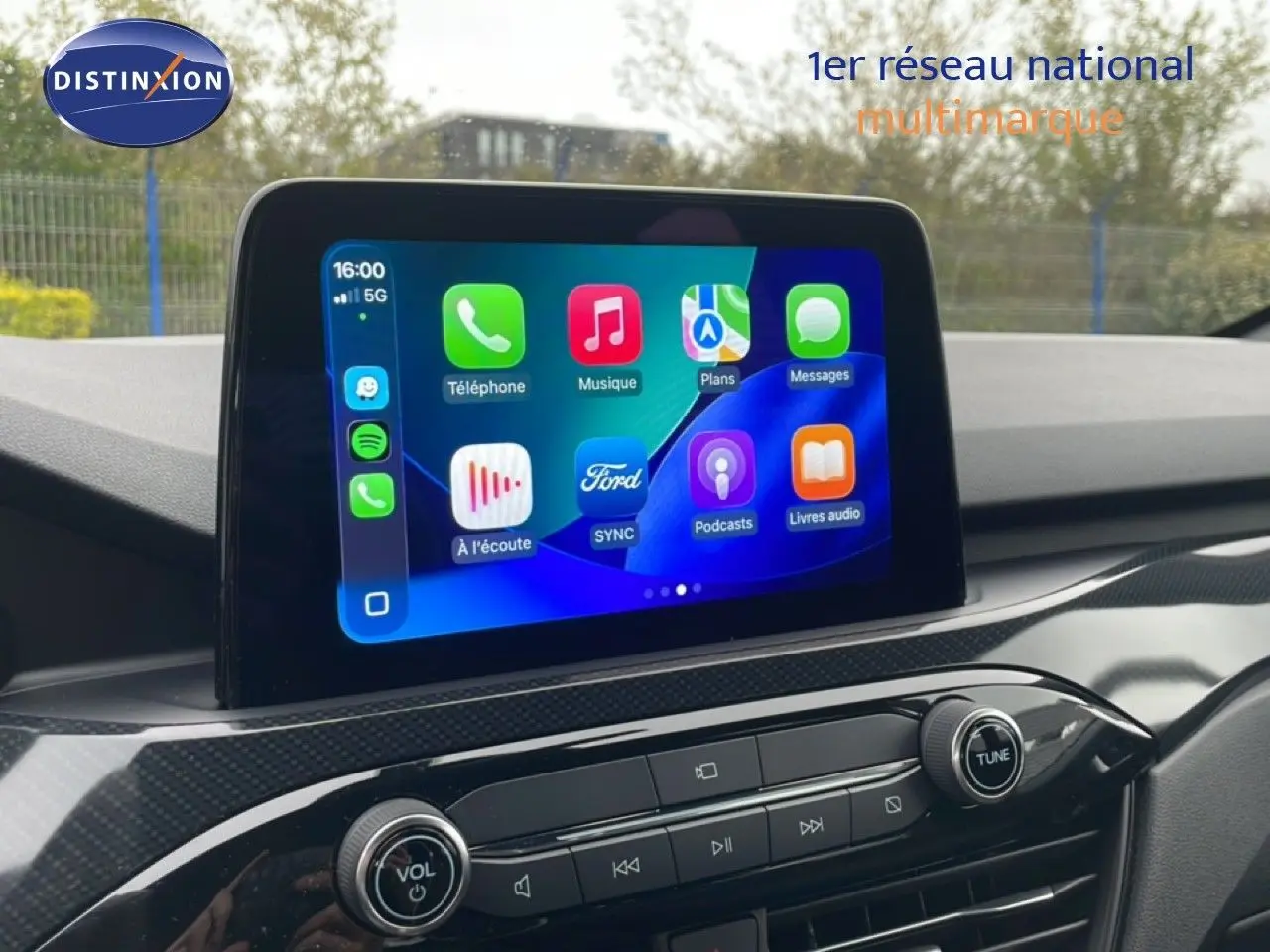 Écran tactile central du Ford Kuga 2024 affichant les applications, avec tableau de bord en finition noire brillante.