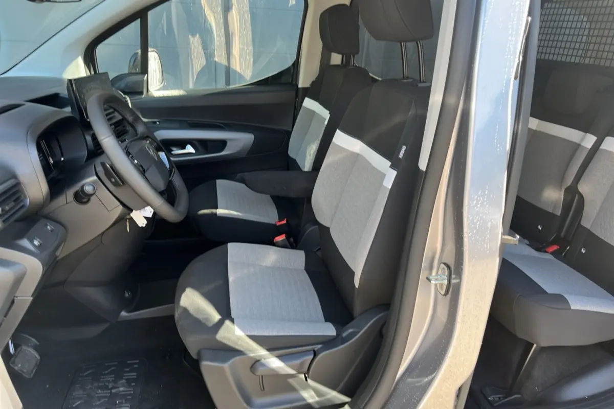 Vue intérieure côté conducteur du Citroën Berlingo gris Artense, montrant les sièges tissu bicolores et le volant multifonctions cuir.