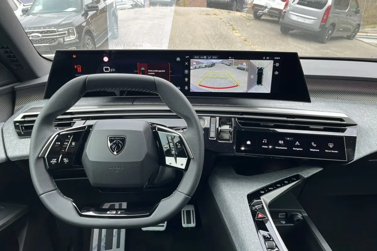 Vue intérieure du tableau de bord du Peugeot 3008 Hybrid 145 GT Alcantara avec volant cuir et écrans digitaux larges.