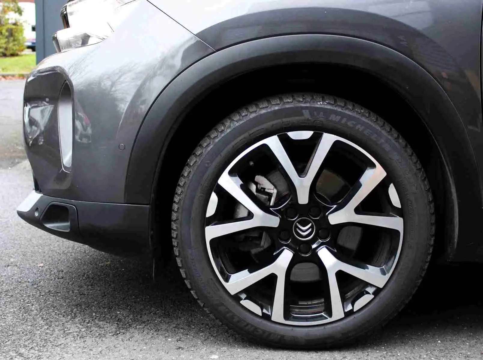 Gros plan sur la roue avant droite d’un Citroën C5 Aircross gris platinium avec jante alliage bicolore et logo Citroën.