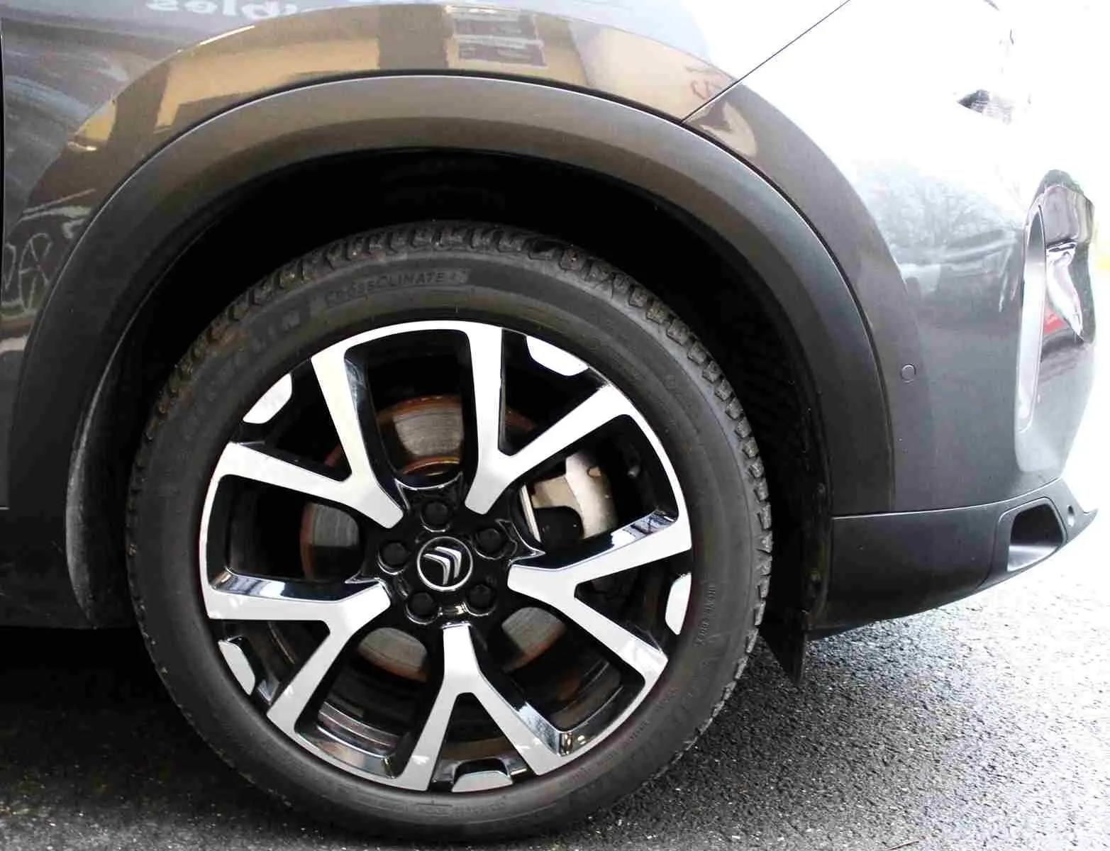 Gros plan sur la roue avant droite du Citroën C5 Aircross gris platinium, mettant en valeur la jante alliage bicolore au design moderne.