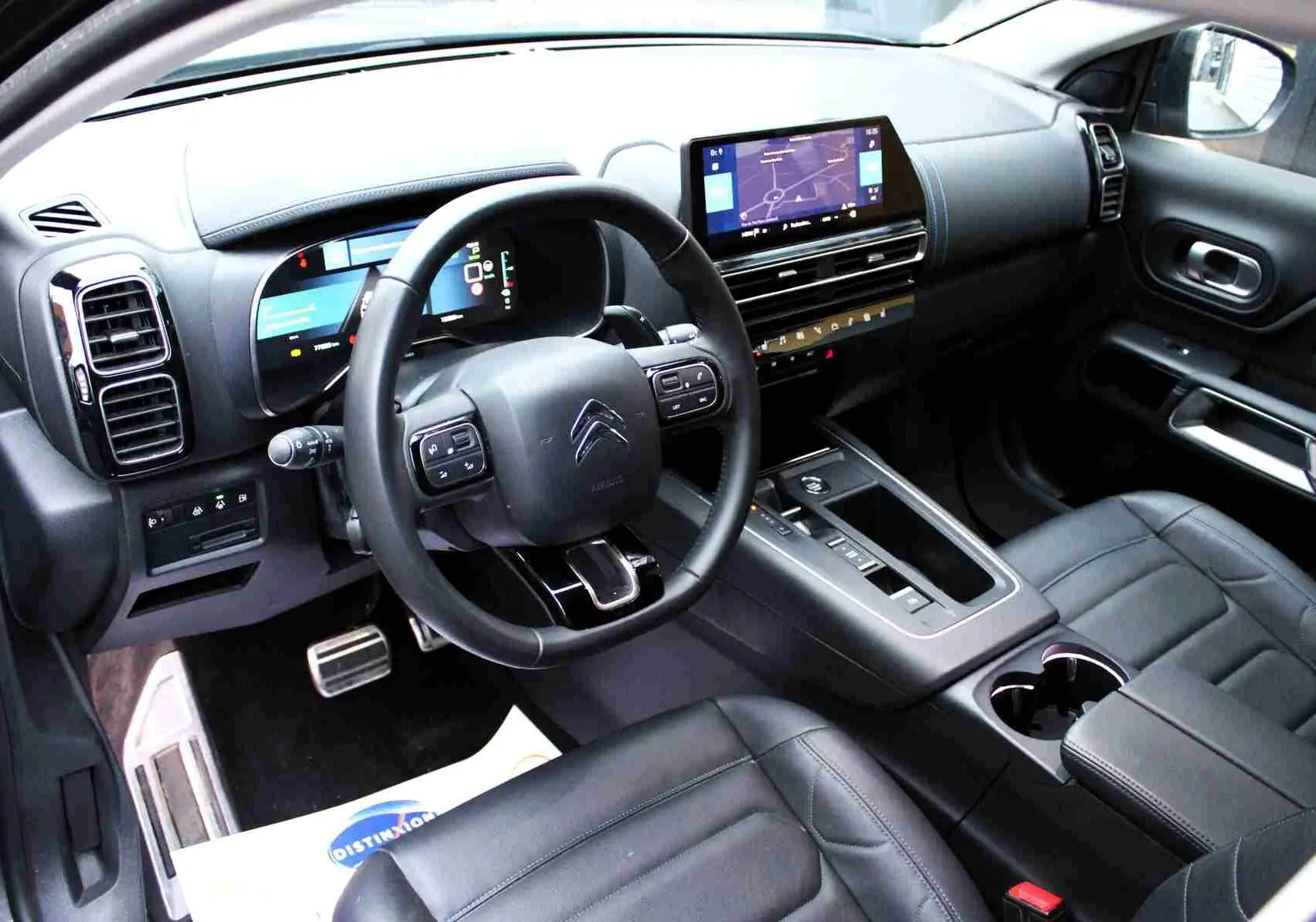 Vue intérieure avant droite du Citroën C5 Aircross hybride gris platinium, avec tableau de bord numérique et sièges cuir noirs.