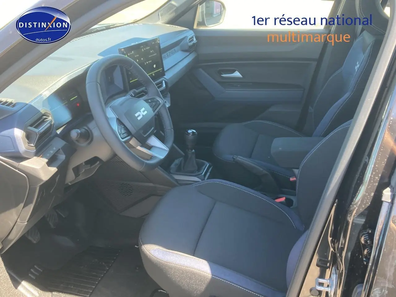 Intérieur noir du Dacia Duster 2025, vue côté conducteur avec volant multifonction et boîte manuelle.