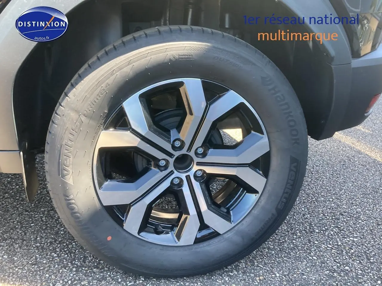 Gros plan sur la jante alu noire et argent du côté droit du Dacia Duster noir 2025.