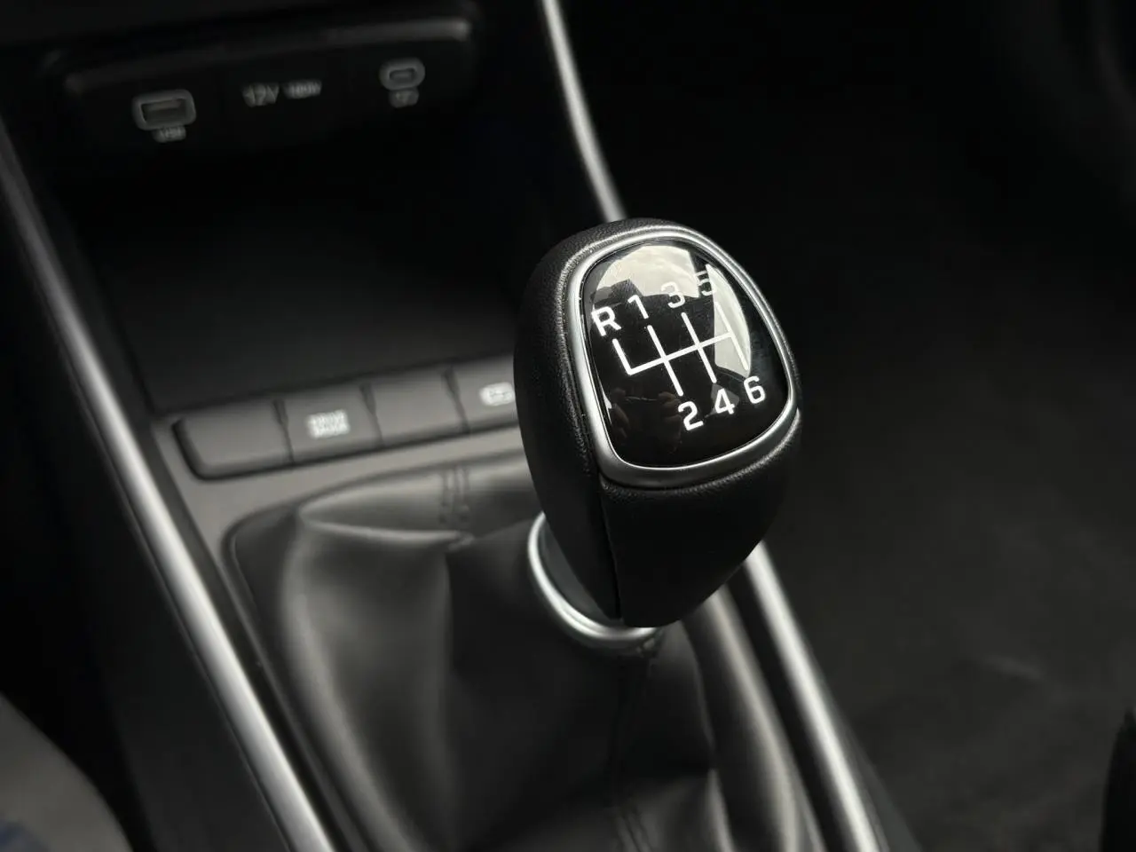 Gros plan sur le levier de vitesses manuel noir de la Hyundai i20 2025, intérieur sobre et moderne.