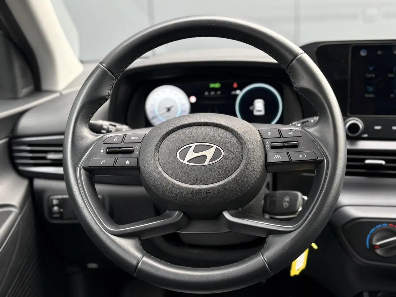 Vue rapprochée du volant cuir noir de la Hyundai i20 2025 avec commandes intégrées et tableau de bord numérique.