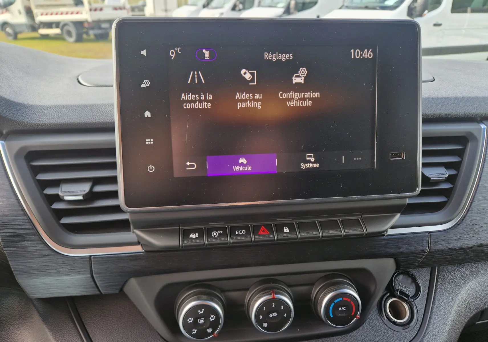 Vue rapprochée de l’écran tactile central et des commandes de climatisation du Nissan Primastar gris urbain, version 2025.