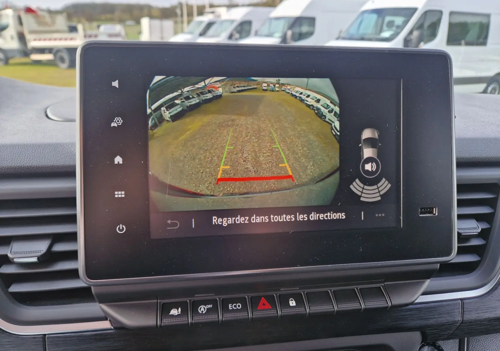 Écran central montrant la caméra de recul du Nissan Primastar gris urbain, vue arrière avec lignes de guidage colorées.