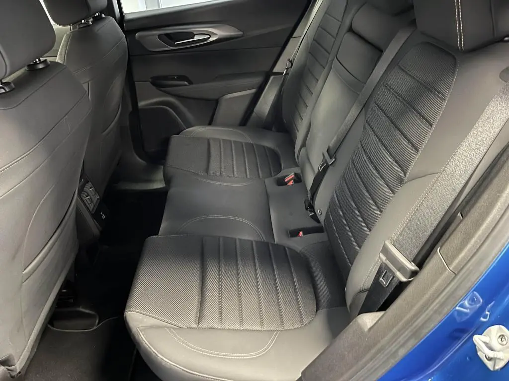 Vue latérale des sièges arrière noirs en tissu AlfaTec avec surpiqûres beige de l'Alfa Romeo Tonale bleu 2024.