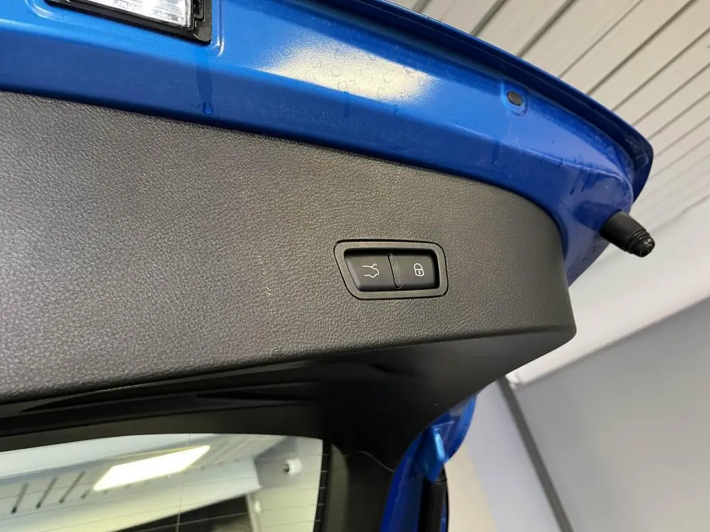 Bouton de fermeture électrique du hayon sur la partie intérieure du coffre bleu d'une Alfa Romeo Tonale 2024.