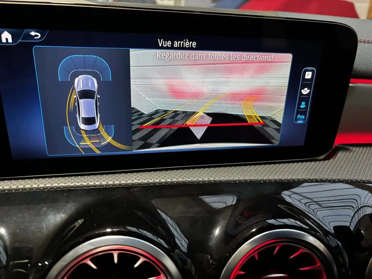 Écran tactile intérieur montrant l’aide au stationnement arrière de la Mercedes CLA 250 e AMG Line blanche.