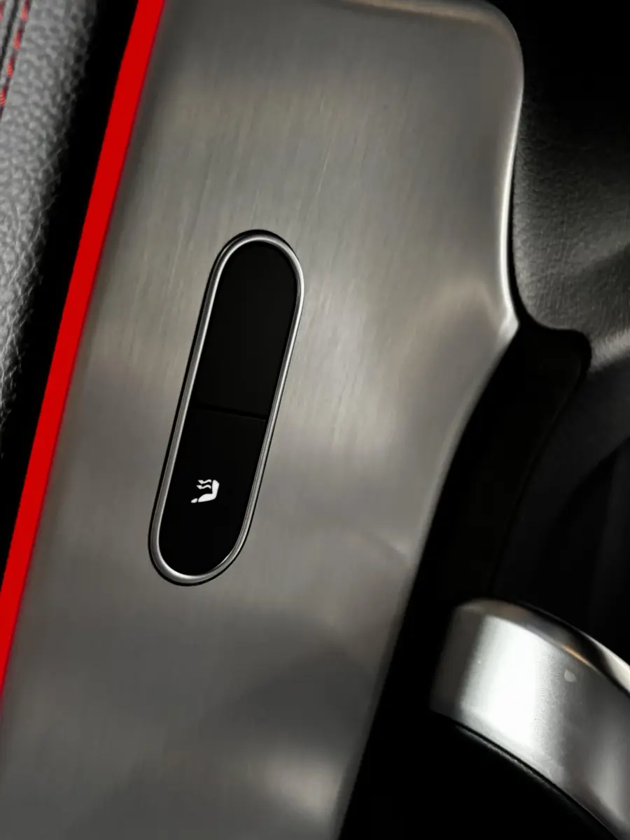 Détail du bouton de ventilation des sièges sur la console en aluminium brossé d'une Mercedes CLA 250 e AMG Line blanche.