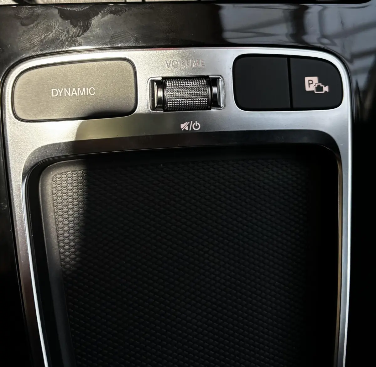 Gros plan sur la console centrale argentée et noire du Mercedes CLA 250 e AMG Line avec boutons Dynamic et contrôle volume.