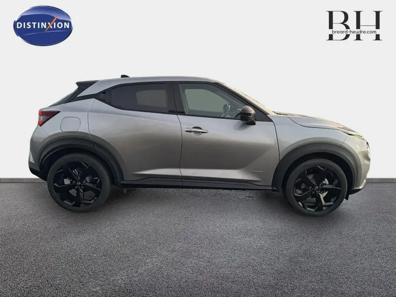 Vue de profil côté gauche du Nissan Juke 1.6 Hybrid Tekna 2025 en gris perle métallisé avec jantes noires distinctives.