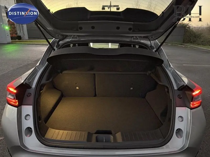 Vue arrière du coffre ouvert d'un Nissan Juke 1.6 Hybrid 143ch Tekna 2025 gris perle métallisé avec feux allumés.