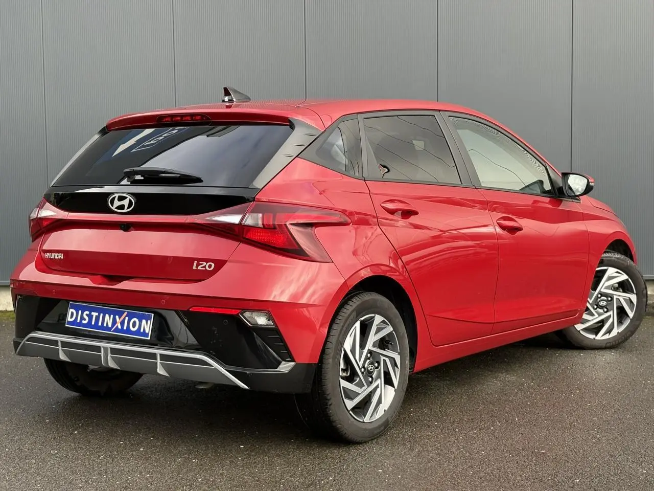 Vue 3/4 arrière droite d'une Hyundai i20 rouge Dragon Metal avec jantes alliage et vitres teintées.