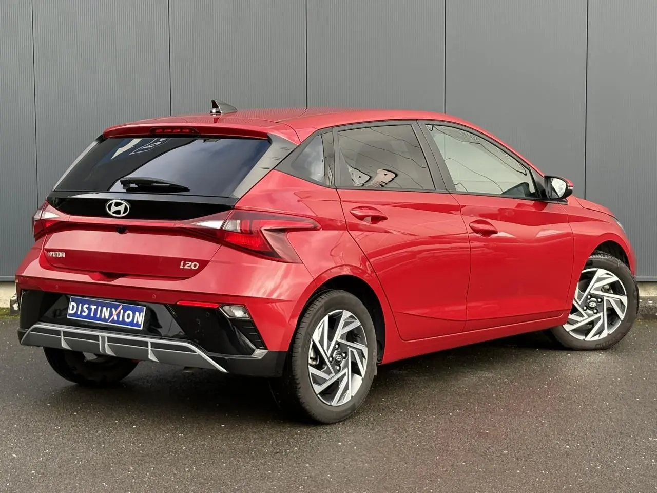 Vue 3/4 arrière droite d'une Hyundai i20 rouge Dragon Metal avec jantes alliage 16'' diamantées et vitres surteintées.