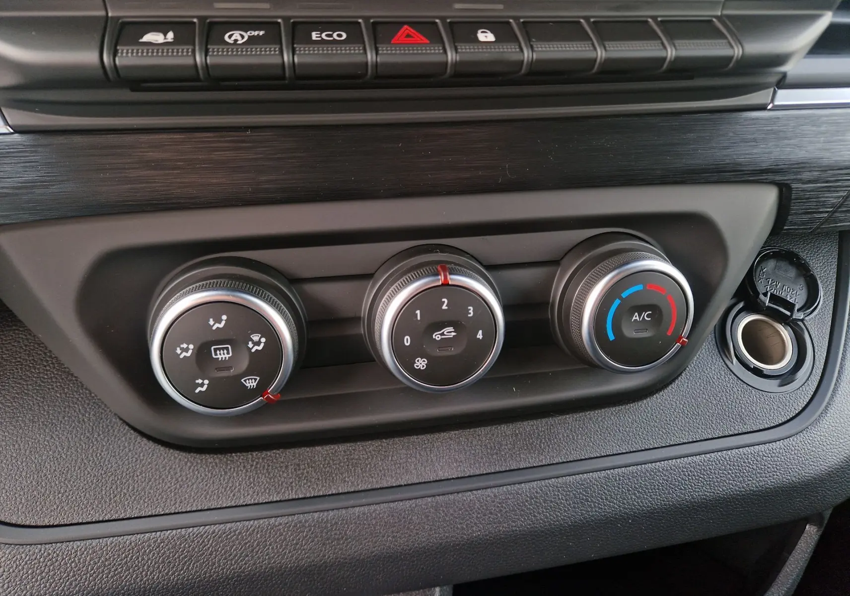 Gros plan sur les commandes de climatisation manuelle et boutons de fonction du tableau de bord du Nissan Primastar gris urbain 2025.