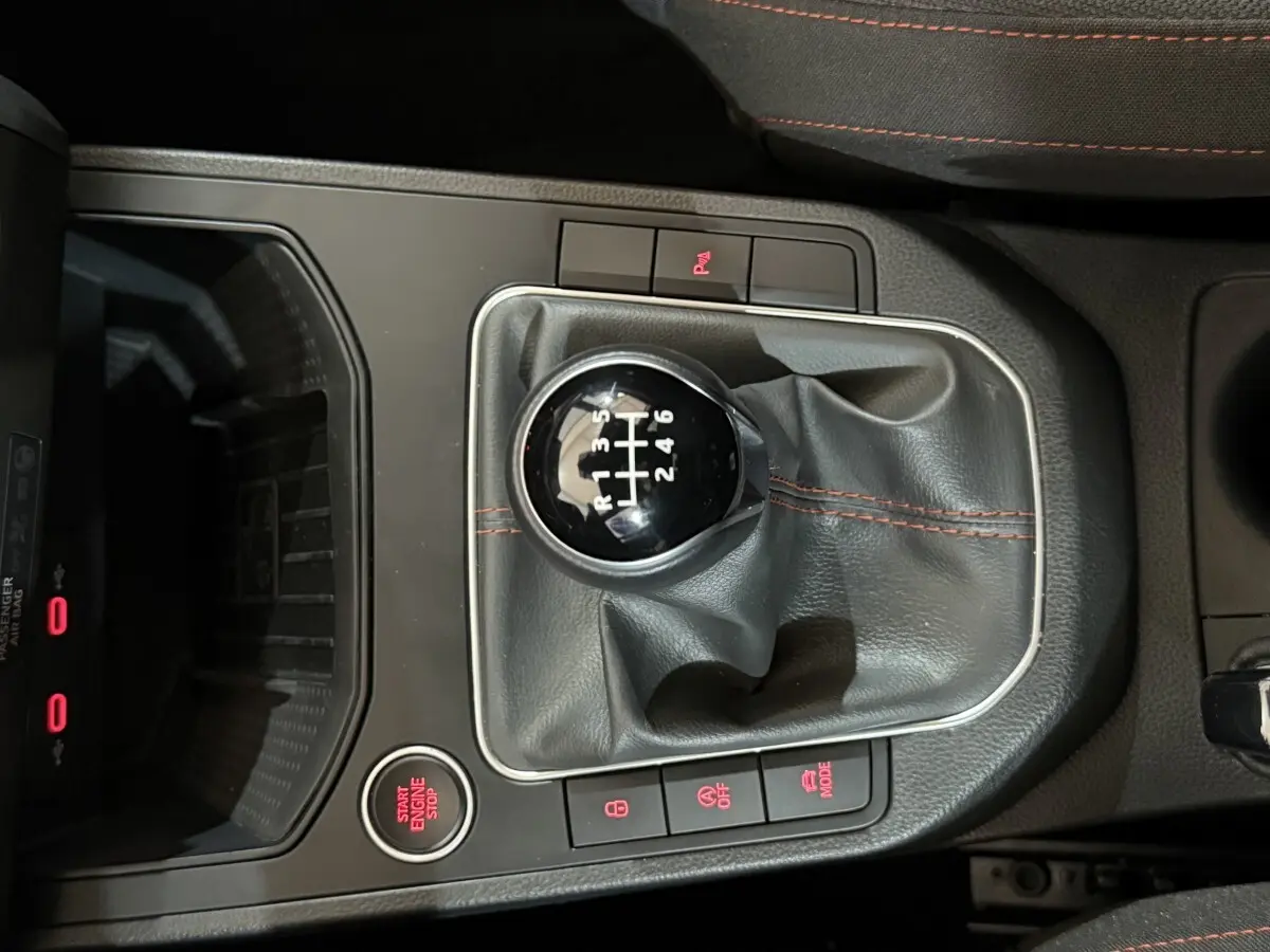 Vue rapprochée du levier de vitesse manuel noir avec coutures rouges dans une SEAT Ibiza blanche 2024.