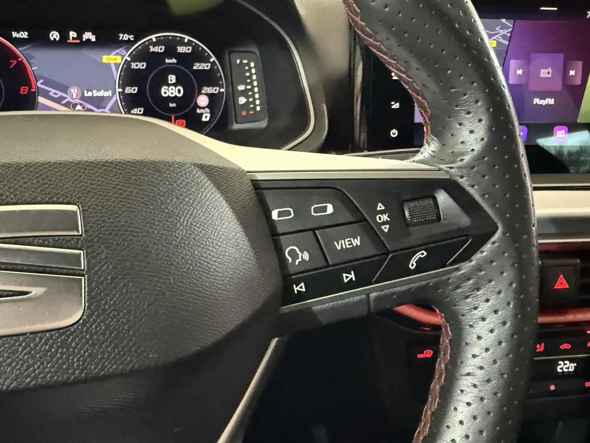 Vue rapprochée du volant cuir perforé noir avec commandes multifonctions et tableau de bord numérique d'une SEAT Ibiza blanche 2024.