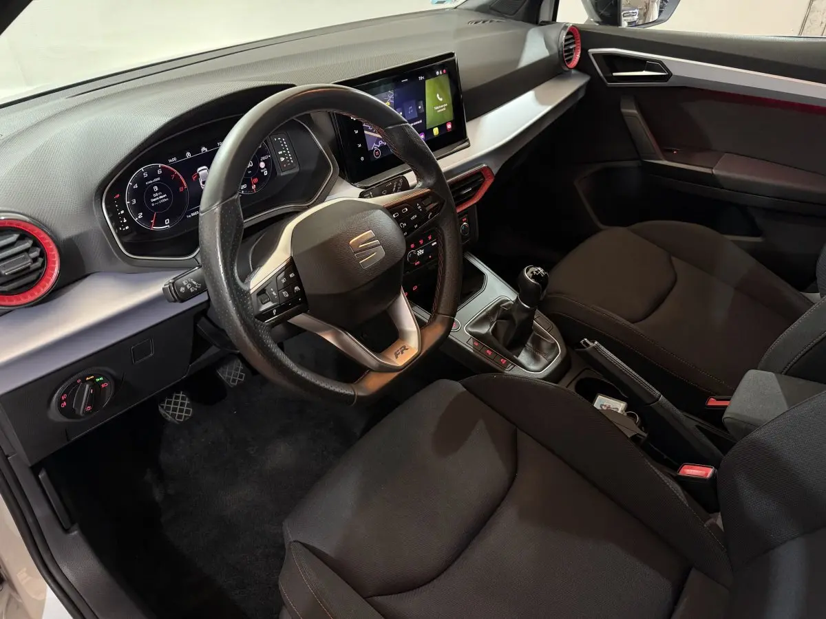 Vue intérieure côté conducteur de la SEAT IBIZA 1.0 TSI 110 FR avec volant cuir, écran tactile et levier de vitesses manuel.