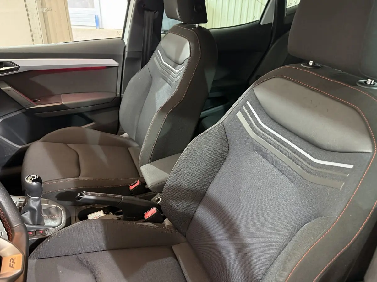 Vue intérieure rapprochée des sièges avant noirs avec surpiqûres rouges et levier de vitesse manuel d'une SEAT Ibiza 2024.
