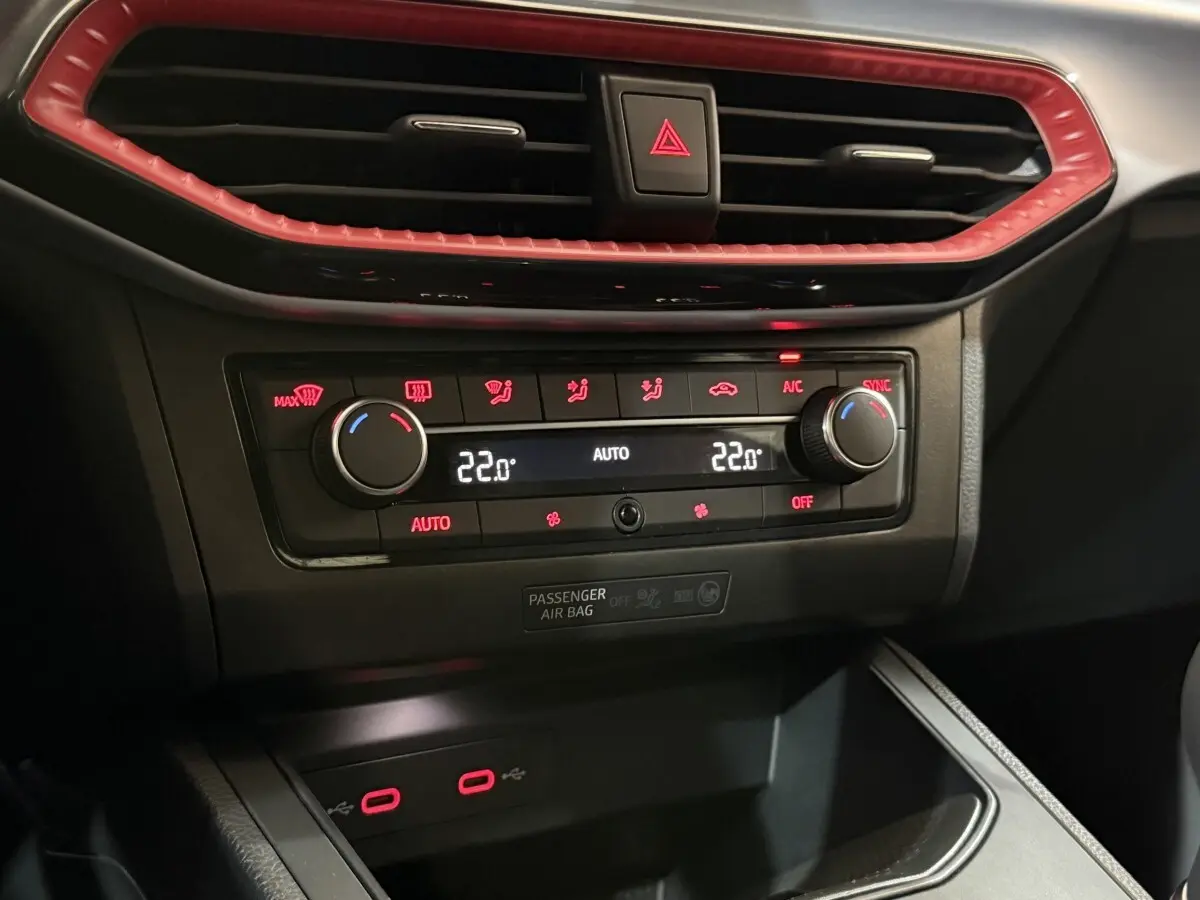 Détail du tableau de bord de la SEAT Ibiza 2024 blanc, montrant la climatisation digitale et les ports USB rouges.