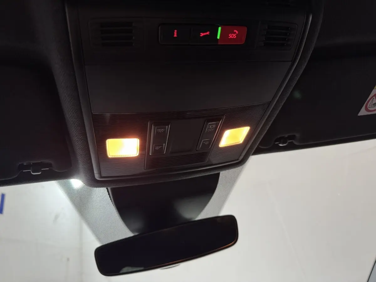 Vue intérieure du plafond avant de la SEAT Ibiza 1.0 TSI 110 FR blanc, avec éclairage et commandes SOS allumées.