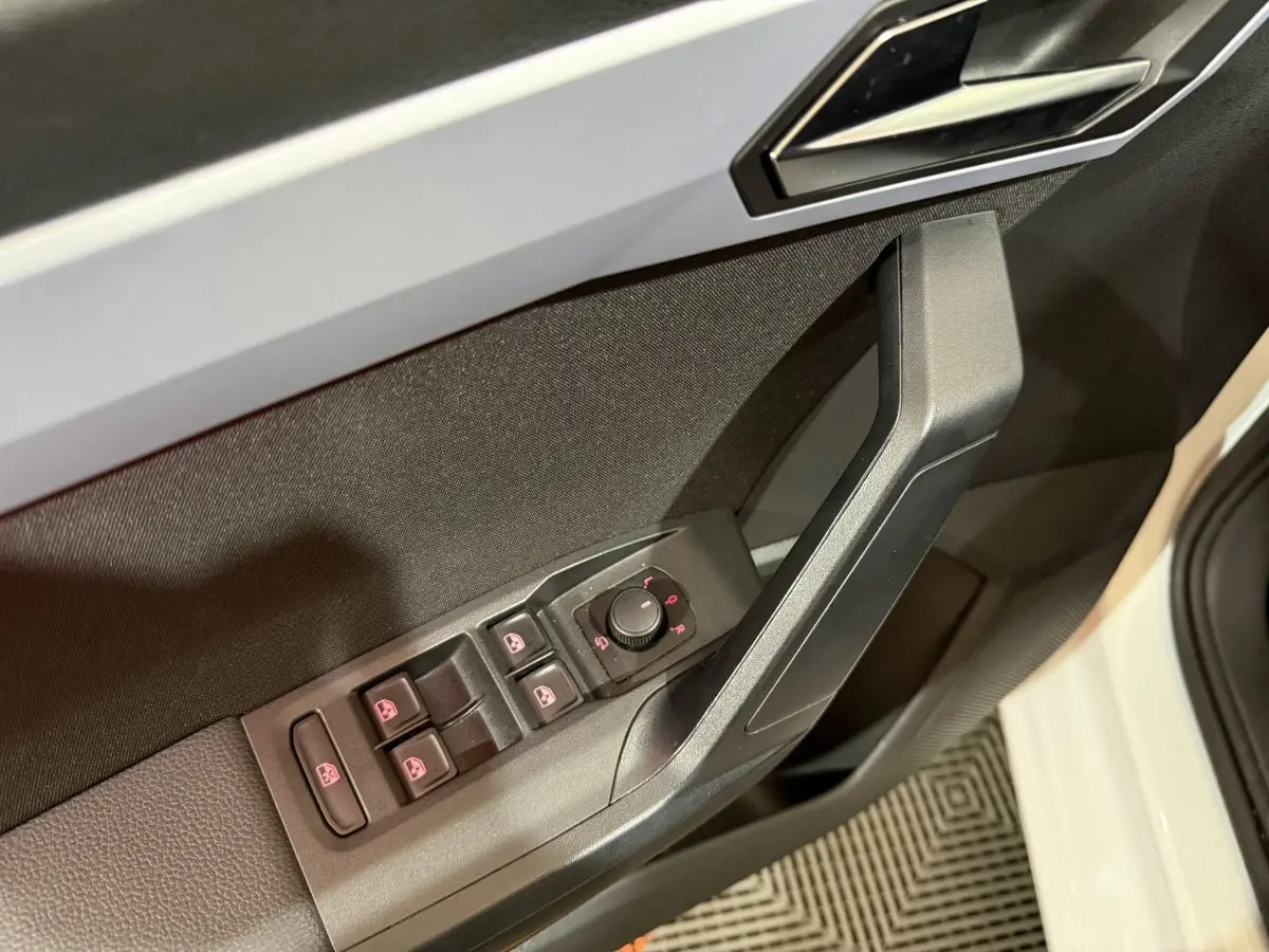 Gros plan sur la commande des vitres et rétroviseurs côté conducteur d’une SEAT Ibiza blanche, porte ouverte.