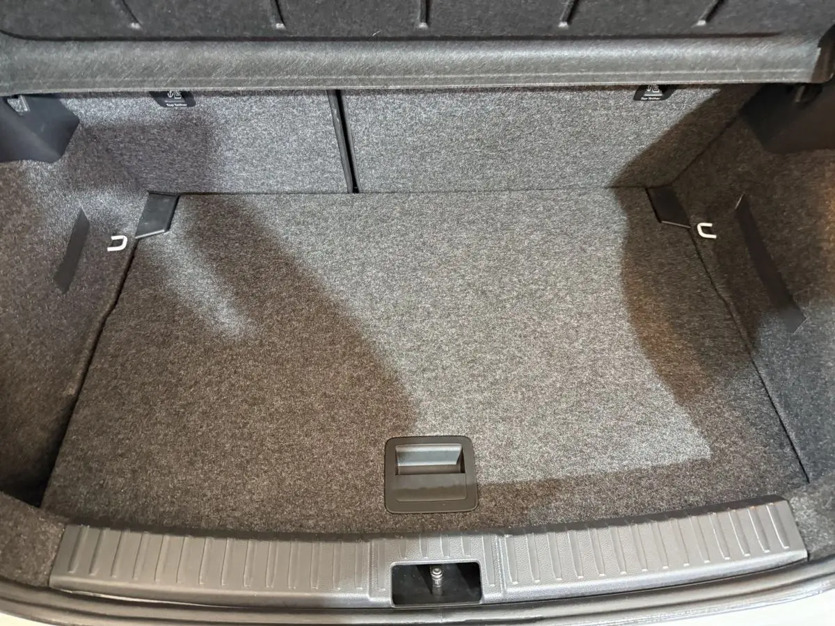 Coffre vide de la SEAT Ibiza 1.0 TSI 110 FR 2024 blanc, vue plongeante sur la surface tapissée et les fixations.