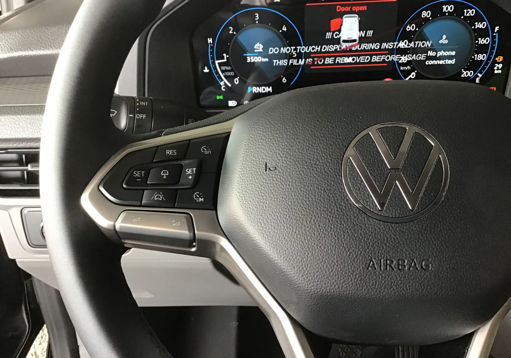 Gros plan sur le volant multifonction et le tableau de bord numérique du Volkswagen Transporter T7 gris anthracite 2025.