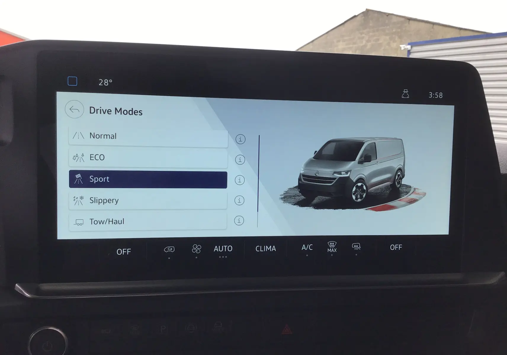 Écran central montrant un Volkswagen Transporter T7 gris anthracite en vue 3/4 avant avec mode de conduite Sport sélectionné.