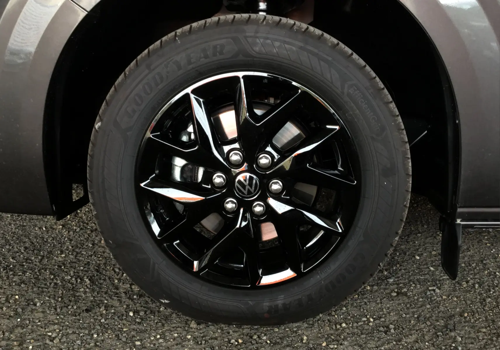 Gros plan sur la roue avant droite du Volkswagen Transporter T7 gris anthracite avec jante noire brillante et pneu Goodyear.