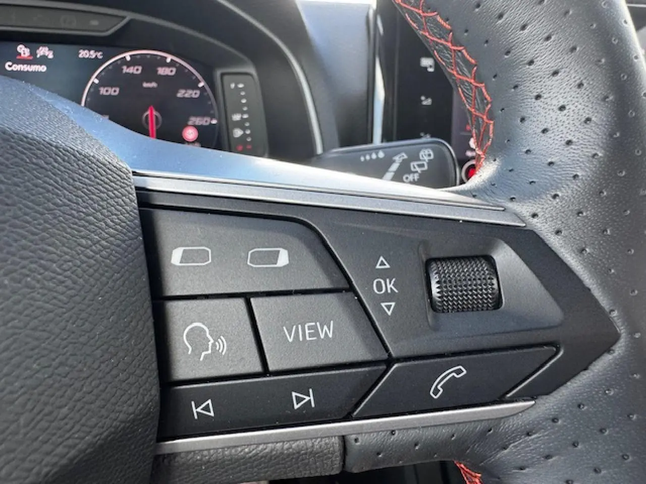 Gros plan sur les commandes du volant perforé avec surpiqûres rouges du SEAT Arona 2024 finition FR.