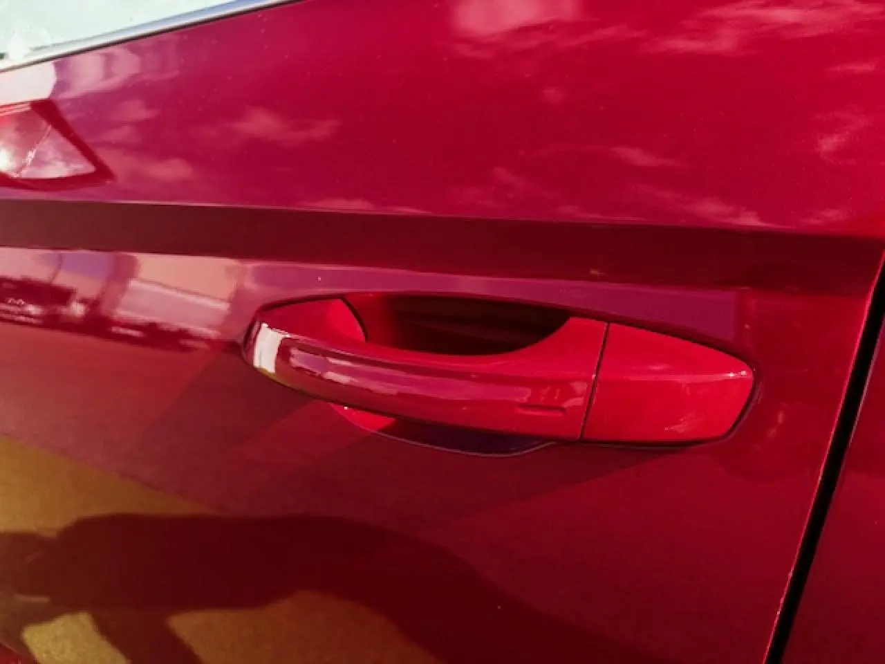 Poignée de porte rouge vif côté gauche d'une SEAT ARONA 2024 avec peinture Rouge Désir et toit noir.