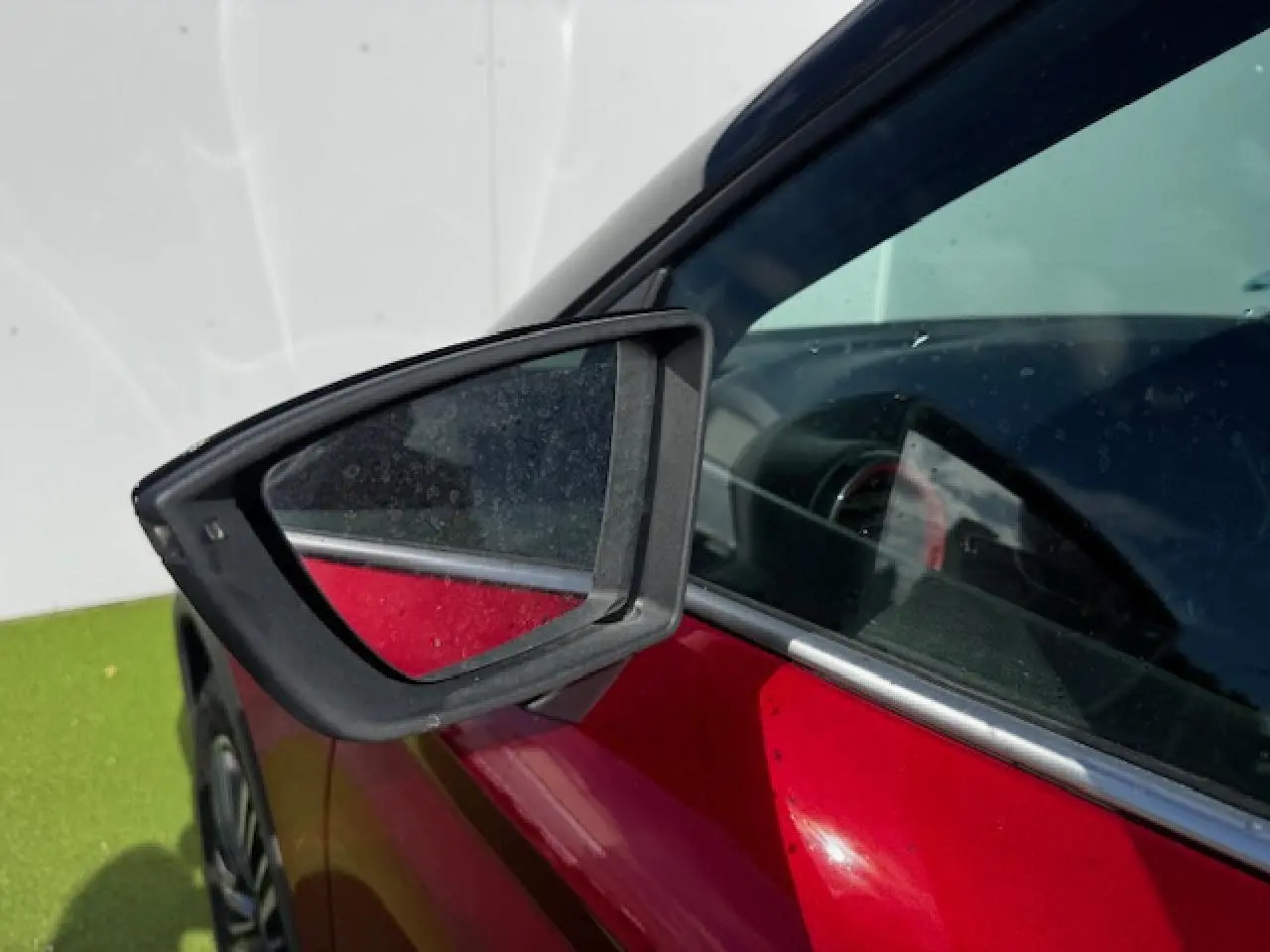 Gros plan sur le rétroviseur côté gauche du SEAT Arona 2024 rouge Désir avec toit noir et vitres teintées.