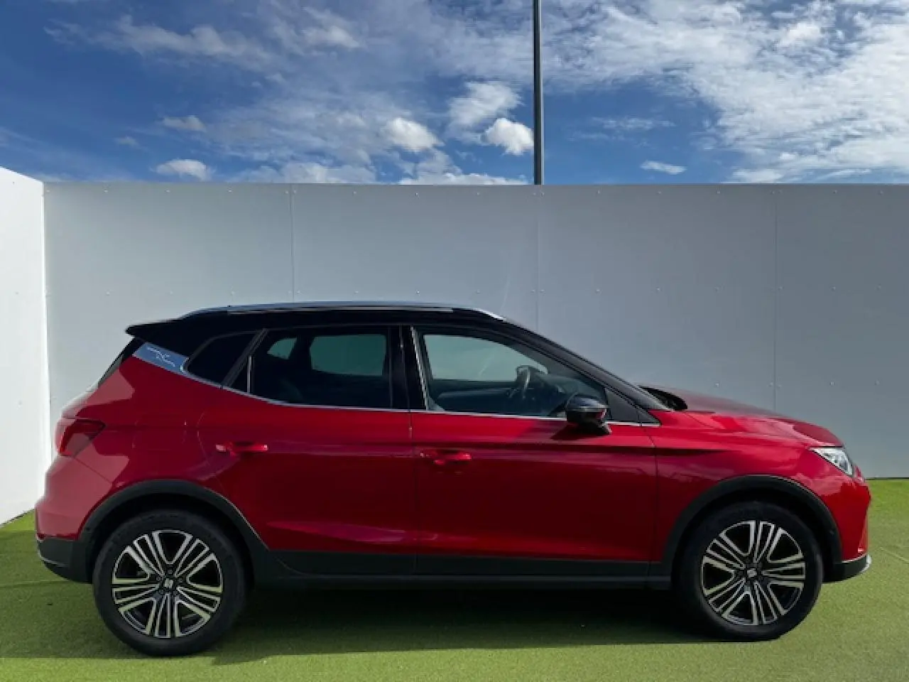 SEAT Arona rouge Désir avec toit noir, vue de profil côté gauche, jantes alliage et vitres teintées.