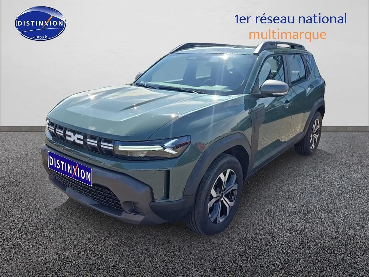 Vue 3/4 avant d’un Dacia Duster vert kaki 2025 avec barres de toit et jantes alu distinctives.