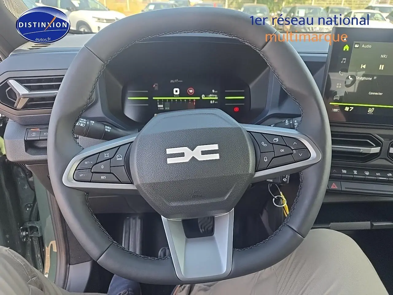Vue intérieure centrée sur le volant multifonction du Dacia Duster vert kaki avec tableau de bord numérique et écran tactile.