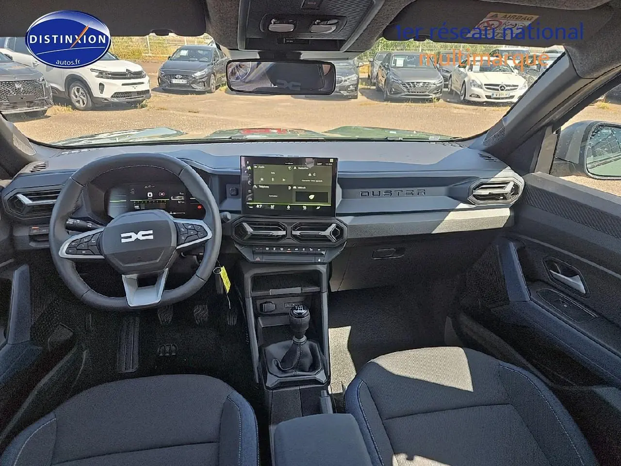Vue intérieure avant du Dacia Duster 2025 avec tableau de bord moderne, écran tactile et volant multifonction noir.