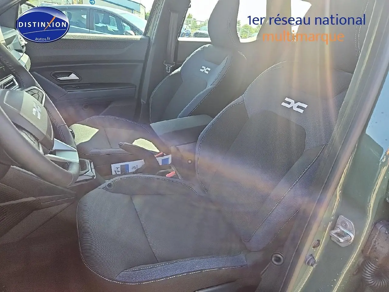 Vue intérieure côté conducteur du Dacia Duster vert kaki 2025, montrant sièges sport avec logo DC et accoudoir central.